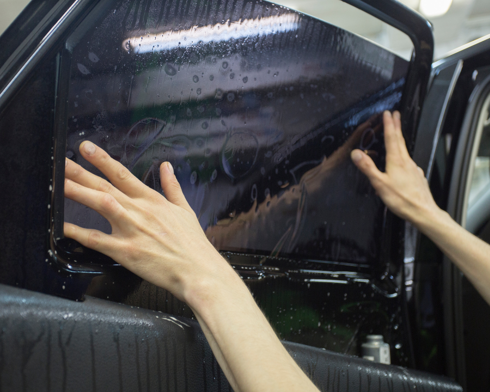 Positioning wet precut tint film against the inside of a side window.