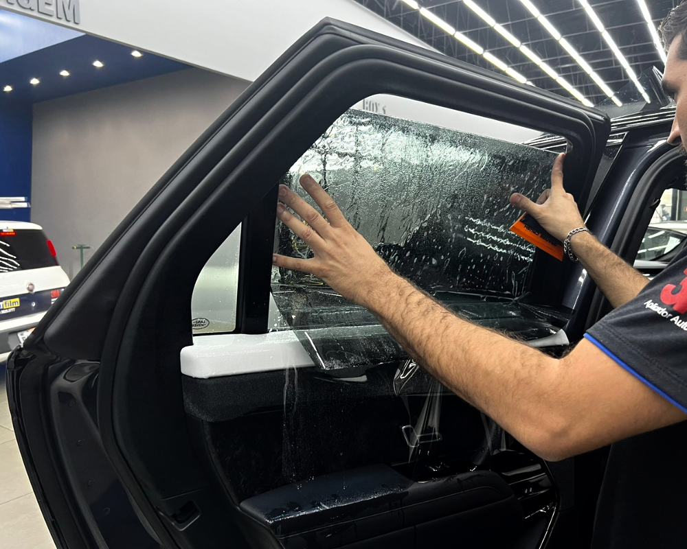 Smoothing tint film into place on the inside of a side window.